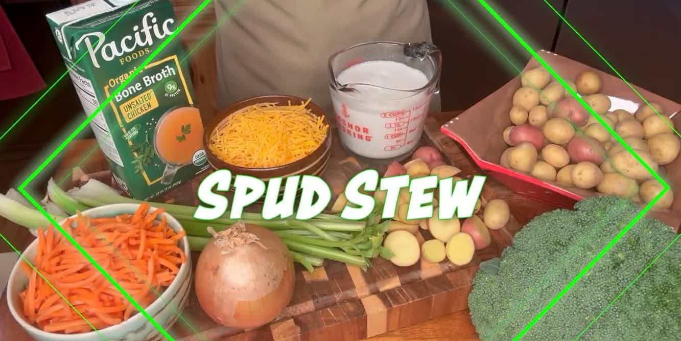 Spud stew video thumbnail showing all of the ingredients needed on a cutting board including bone broth, shredded cheese, shredded carrots, milk, broccoli, onion, celery and small potatoes